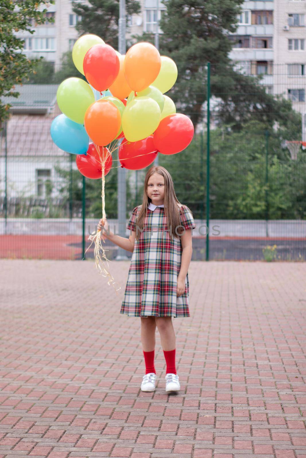 charming teenage girl in checkered brown dress with bunch of colorful balloons. school girl. pretty tween by oliavesna