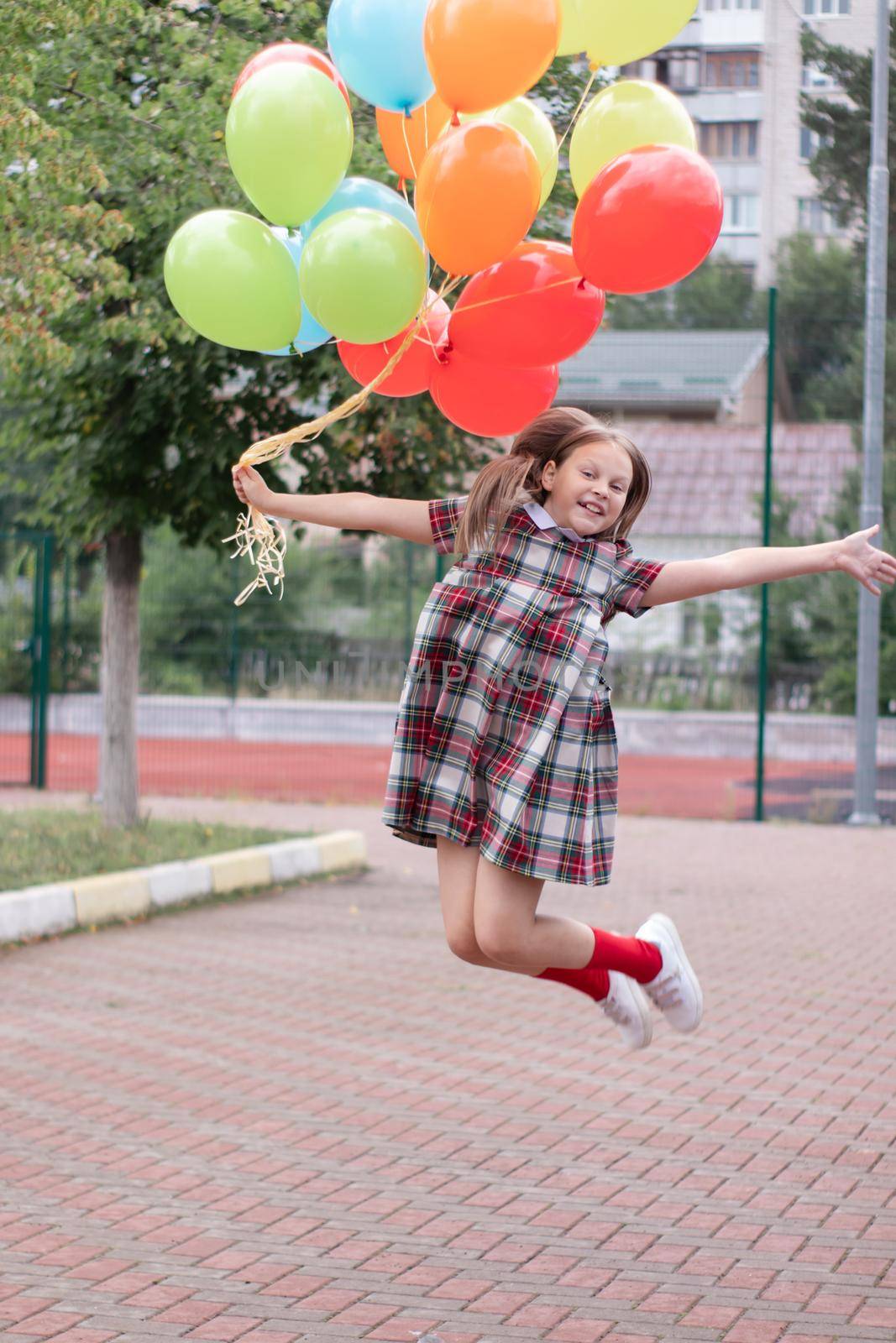 charming teenage girl in checkered brown dress with bunch of colorful balloons. school girl. pretty tween by oliavesna