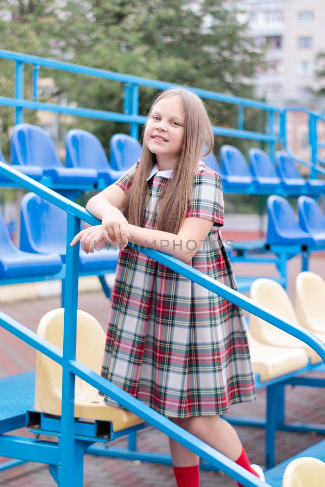 Stadium tribune. tweet brunette girl in dress near Tribunes and plastic colorful chairs in the sports stadium