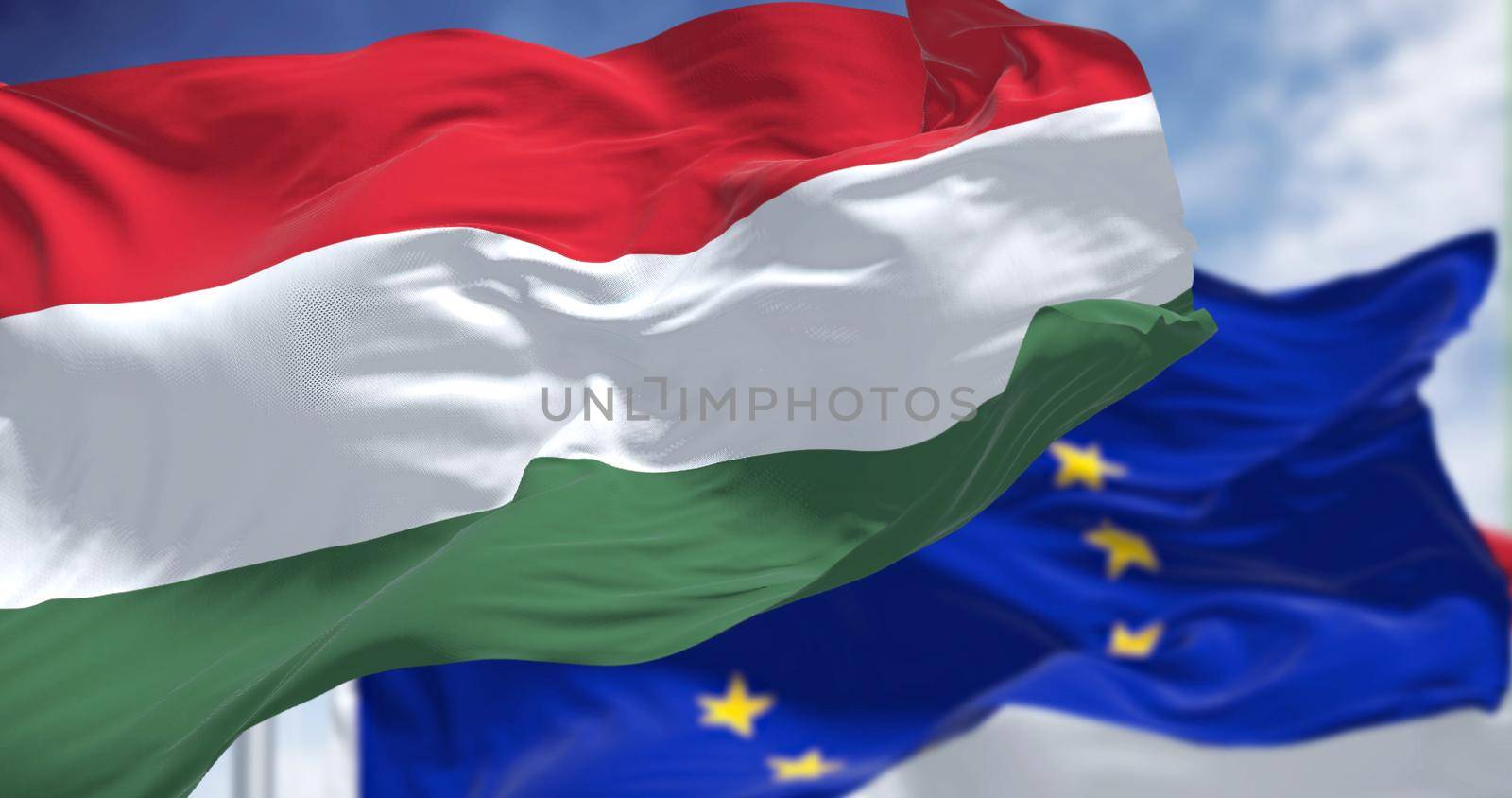 Detail of the national flag of Hungary waving in the wind with blurred european union flag in the background by rarrarorro