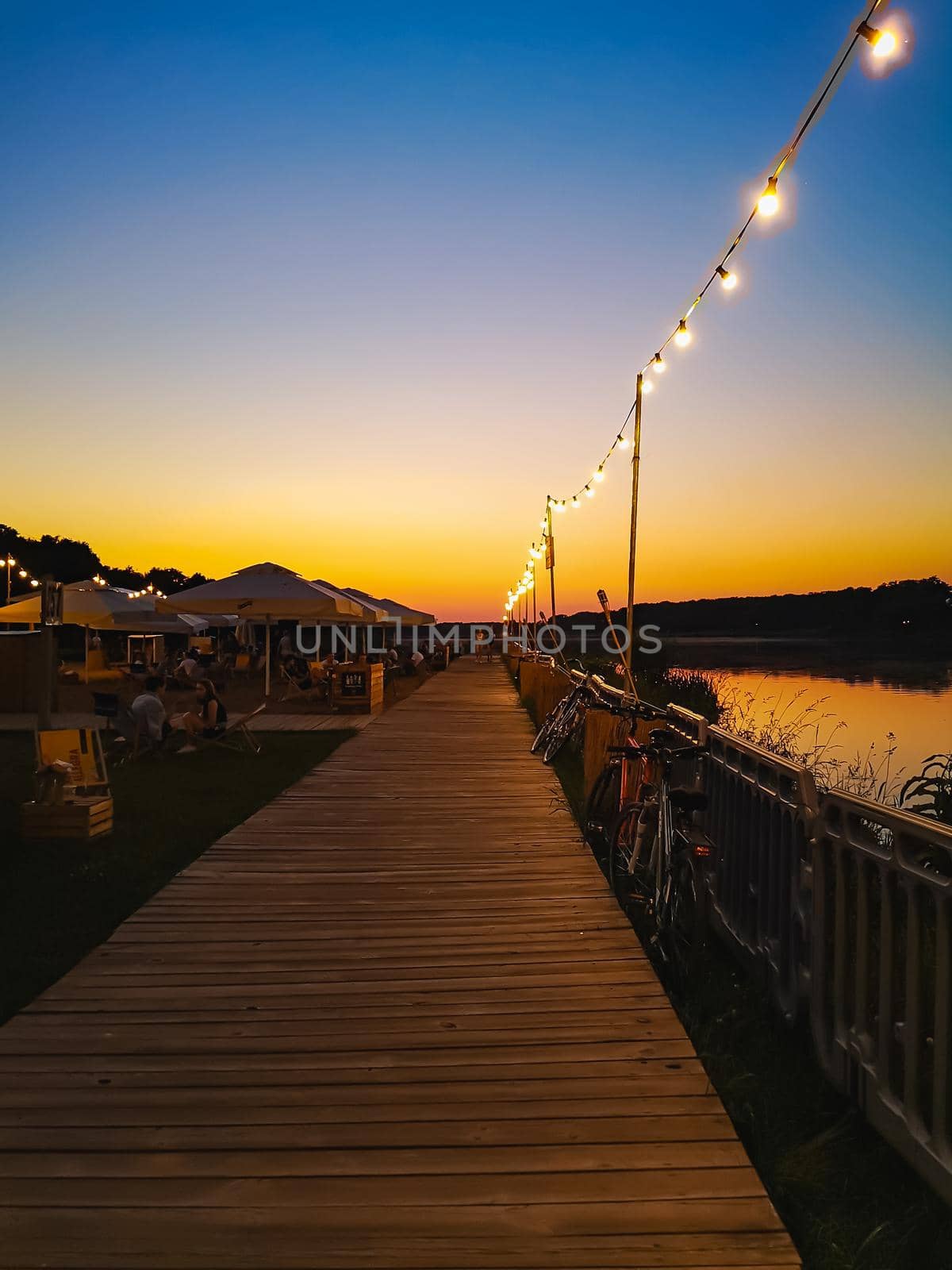 Beautiful sunset over small beach bar next to Odra river full of small decorative bulb lights around