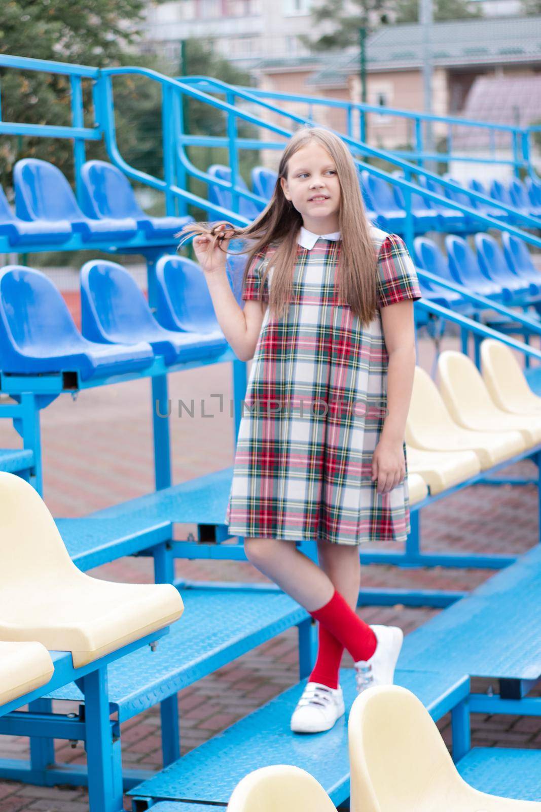 Stadium tribune. tweet brunette girl in dress near Tribunes and plastic colorful chairs in the sports stadium. by oliavesna