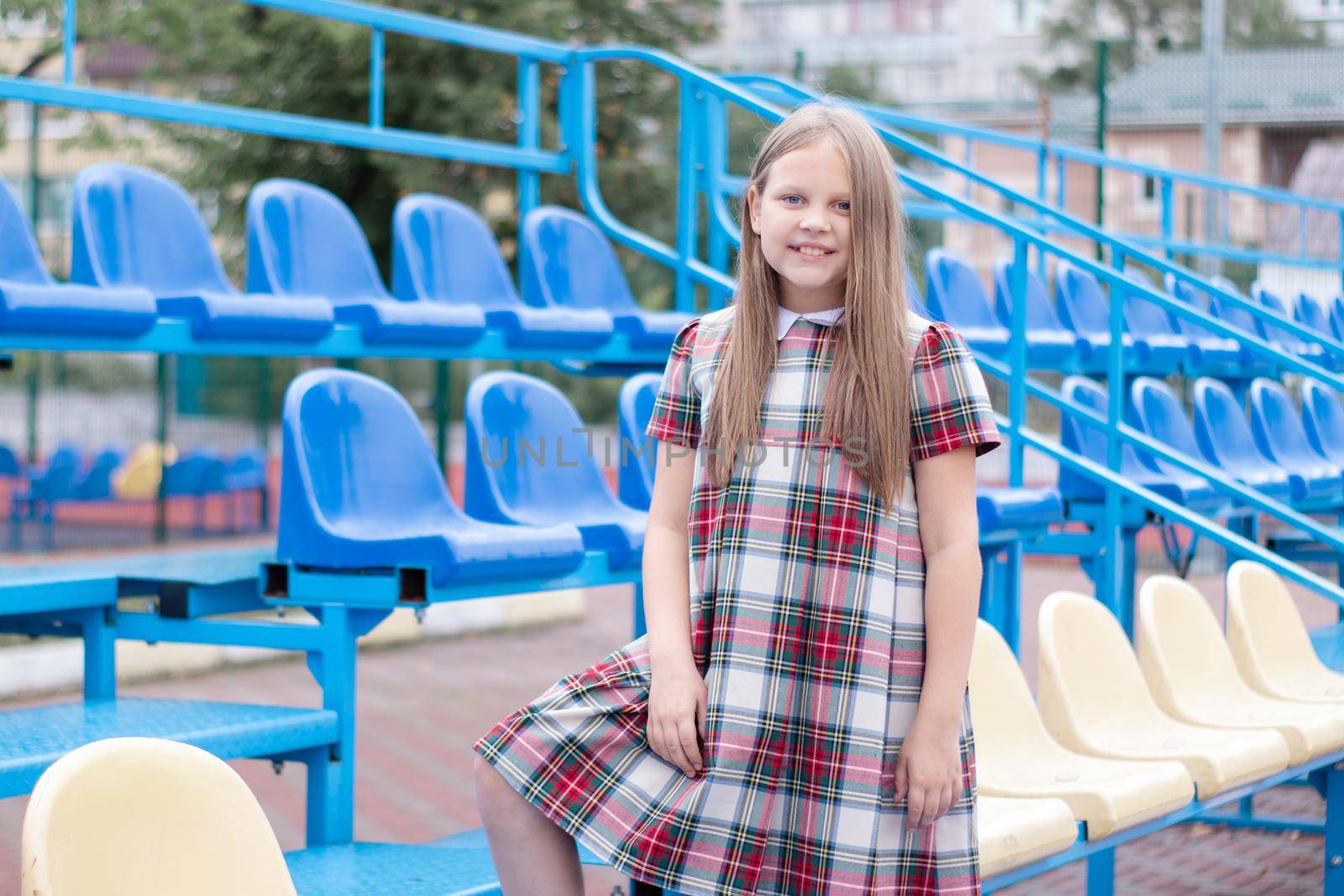 Stadium tribune. tweet brunette girl in dress near Tribunes and plastic colorful chairs in the sports stadium