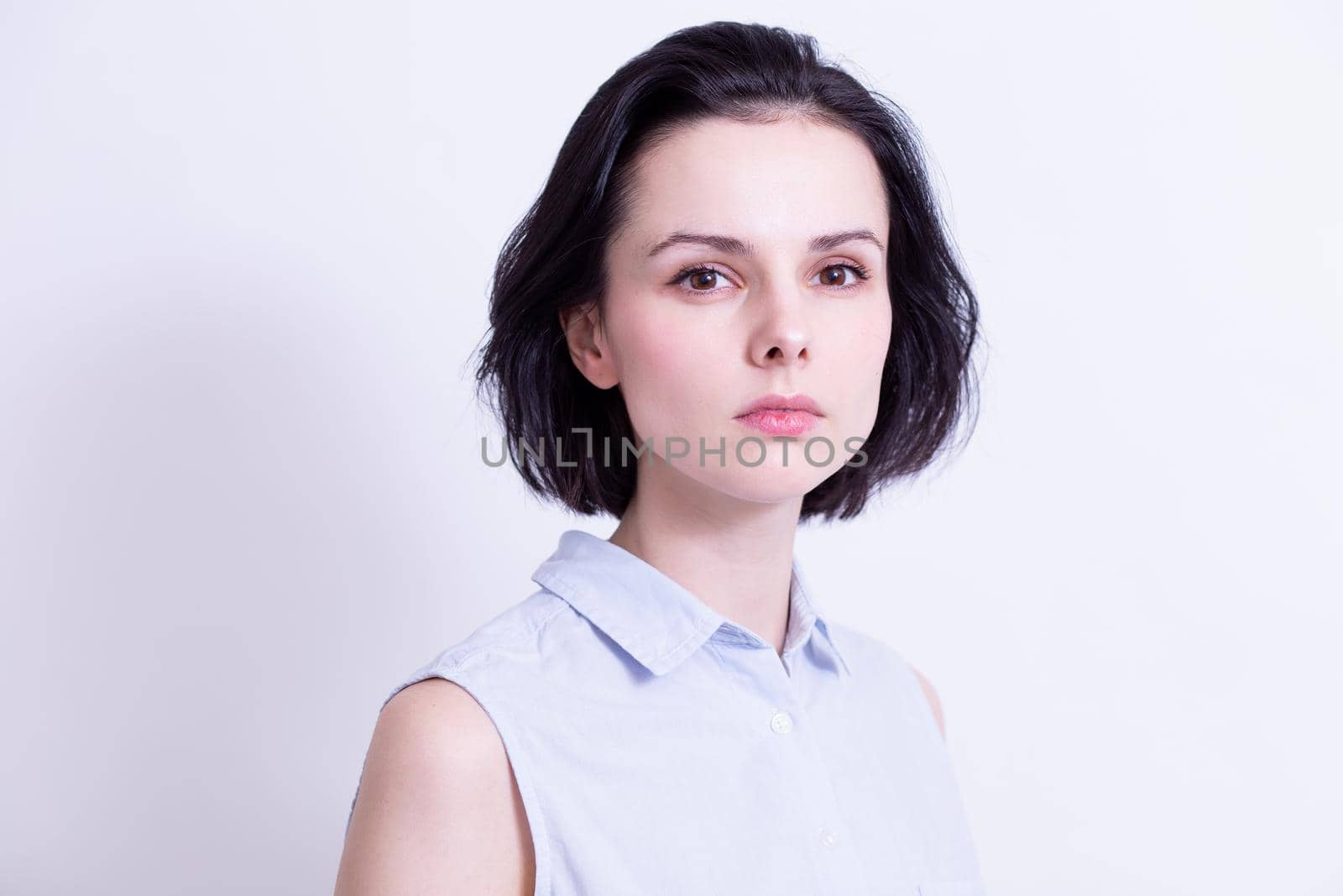 woman in a blue sleeveless office shirt, light background. High quality photo