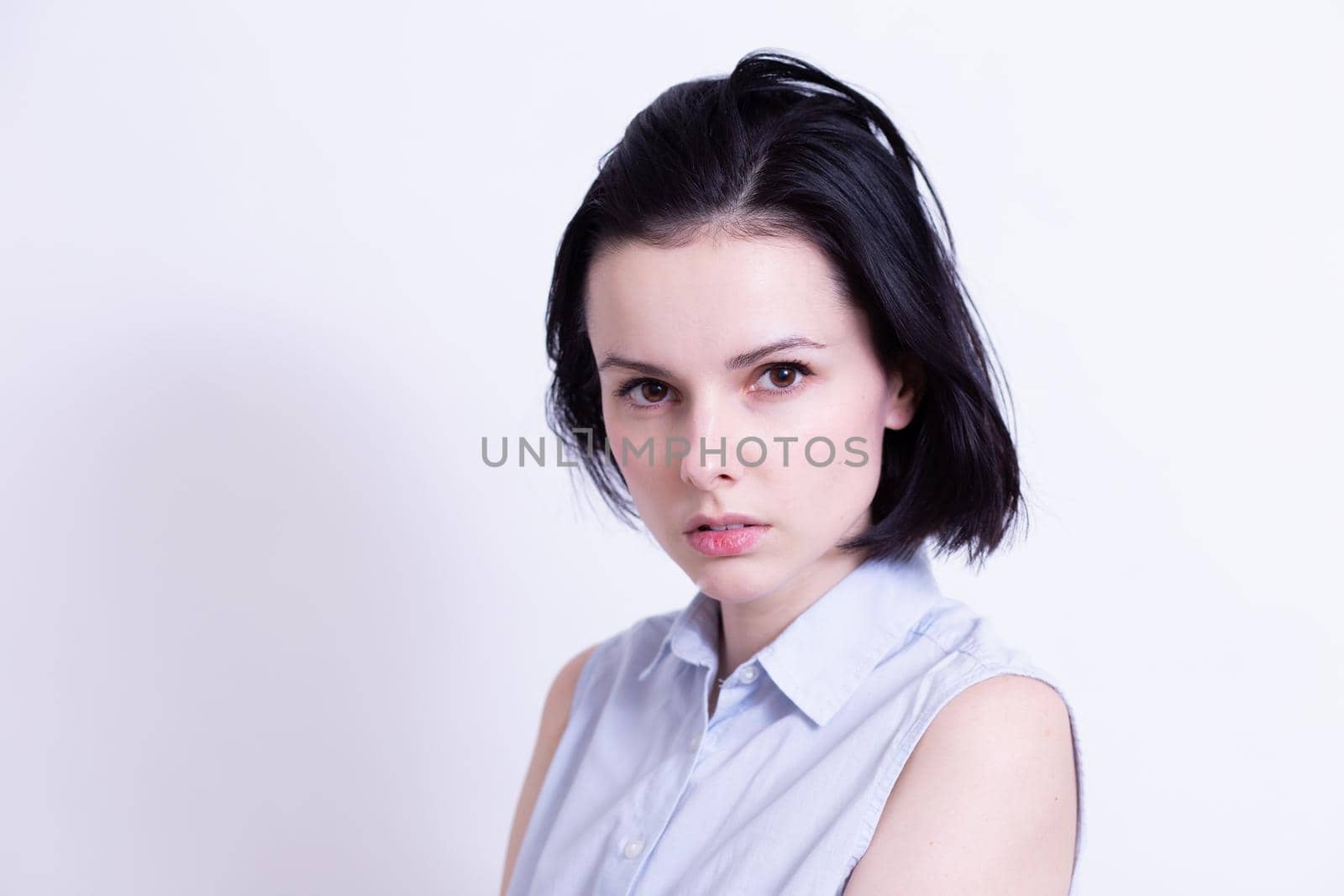 woman in a blue sleeveless office shirt, light background. High quality photo