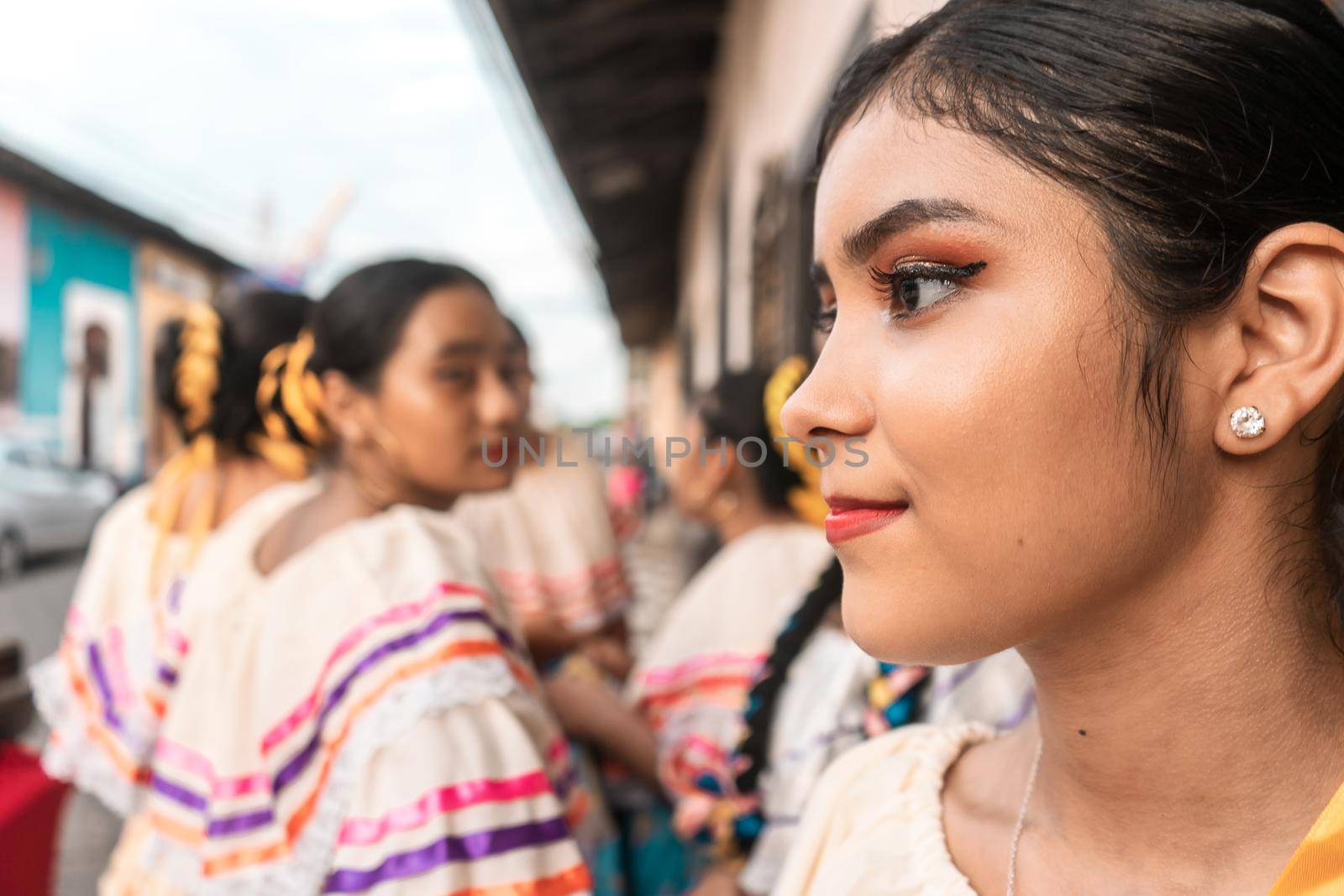 Latin young woman dressed in traditional costume of Nicaraguan folklore with her group of friends in the background in Leon by cfalvarez