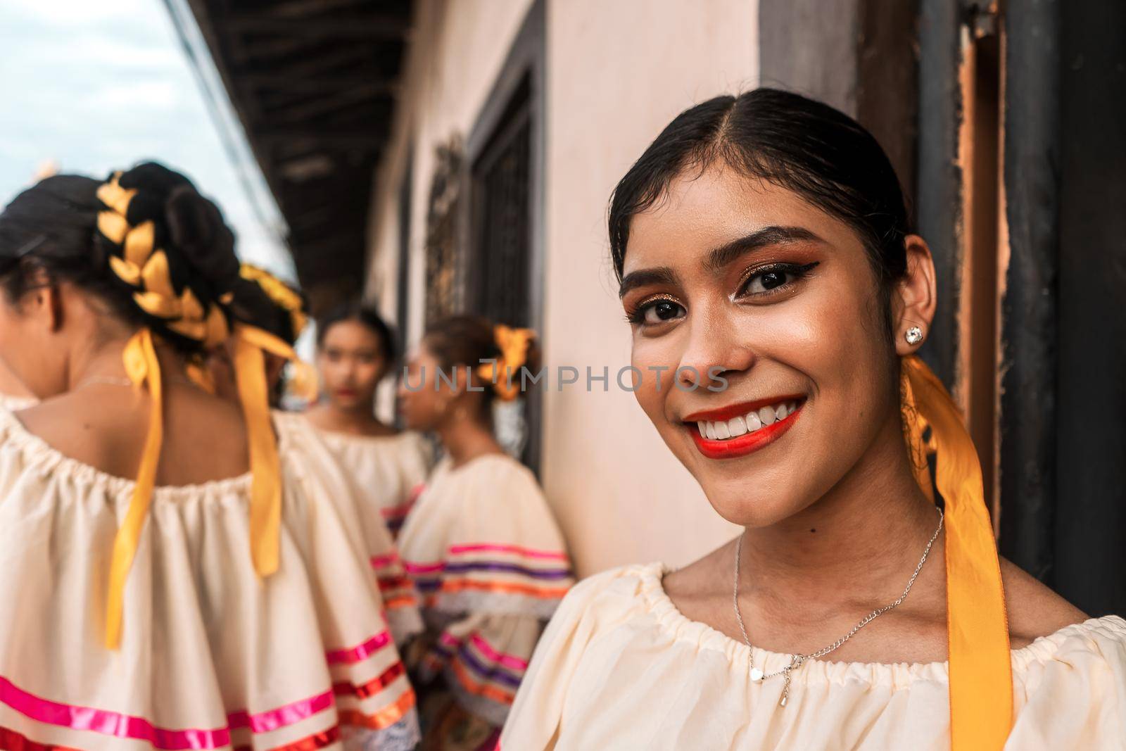 Pretty young latin woman smiling and looking at camera wearing folkloric dress from Nicaragua. Group of young friends in Latin America.