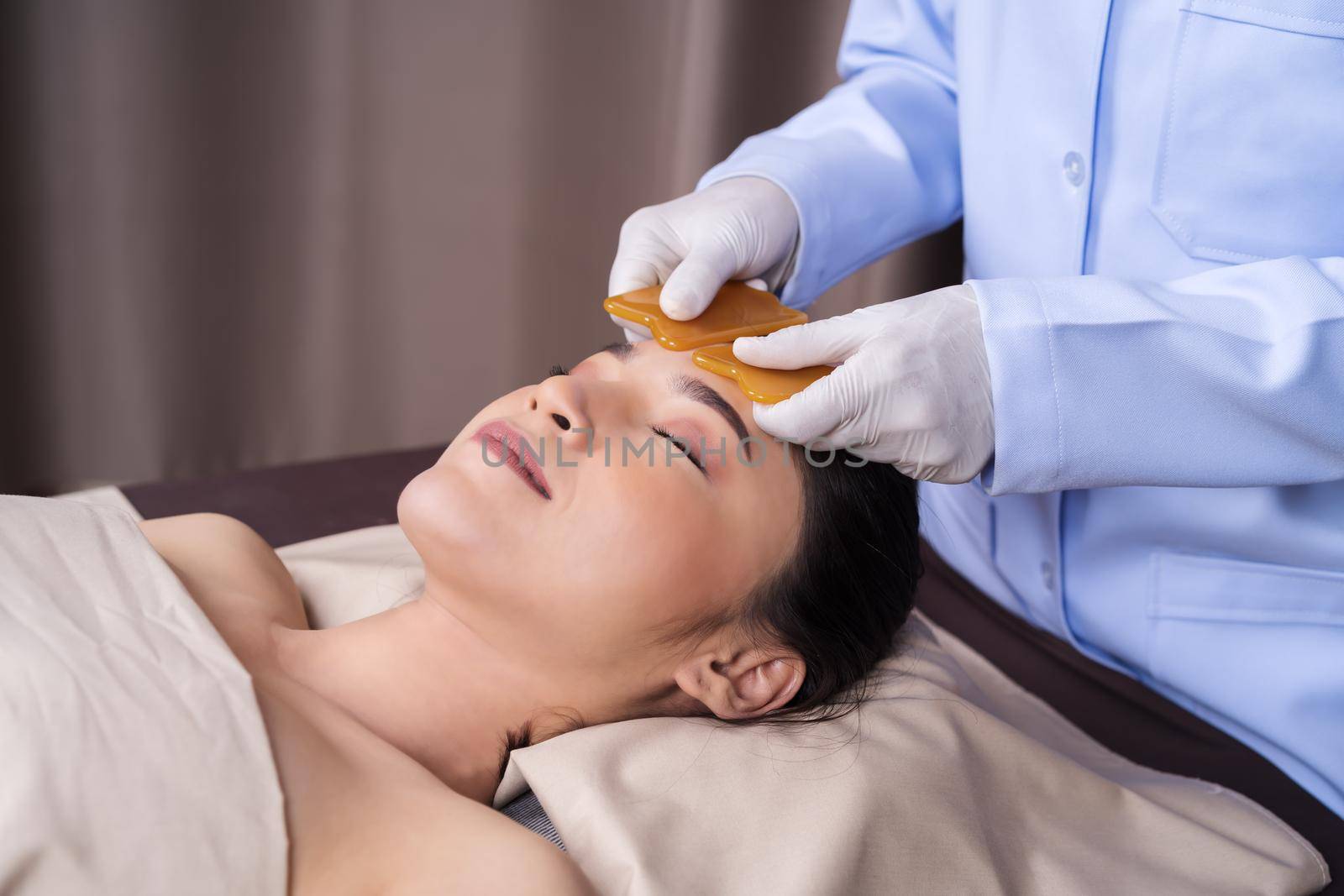 young woman receiving traditional guasa face therapy