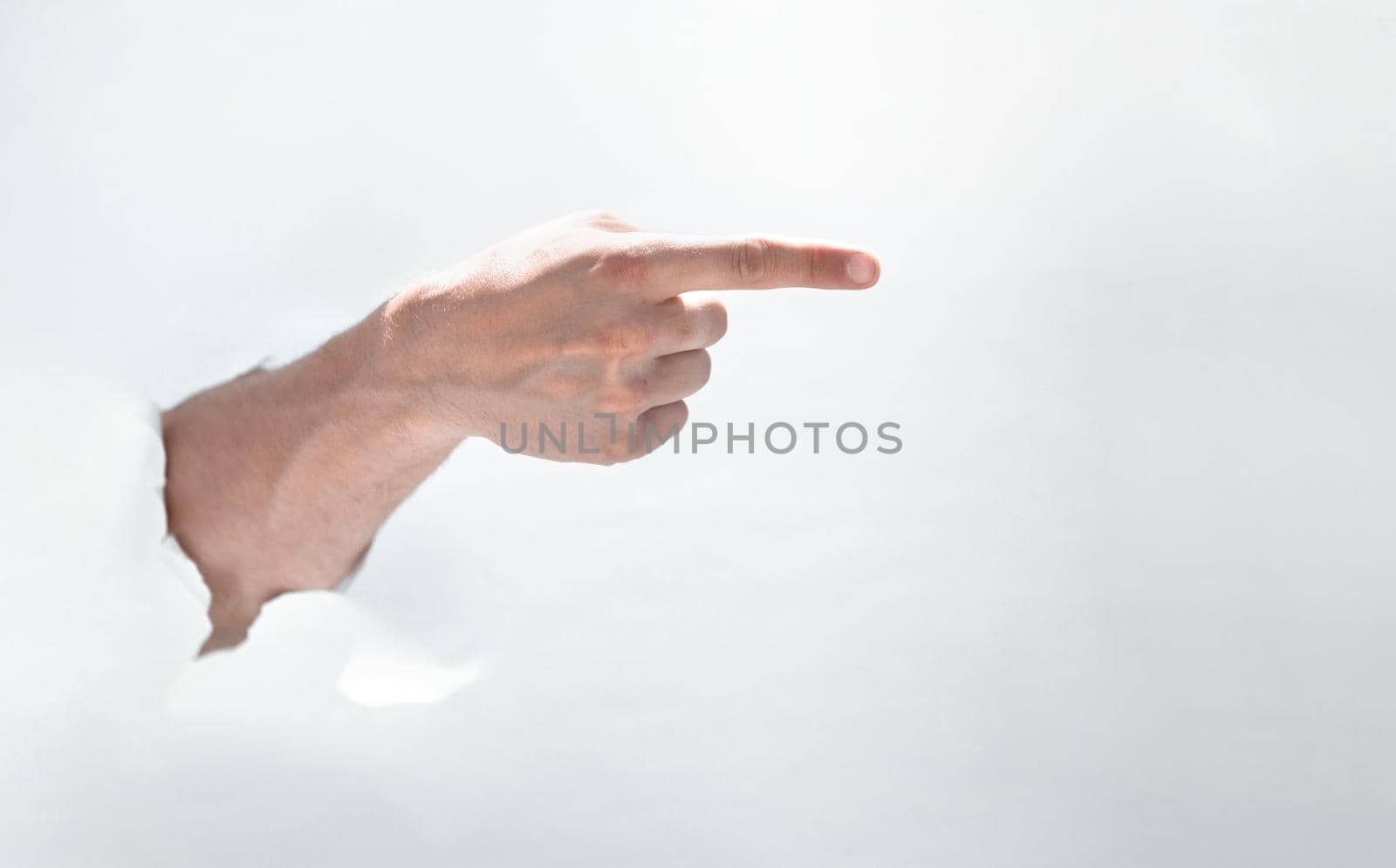 man hand breaking through the paper and pointing to a copy of the space.photo with space for text