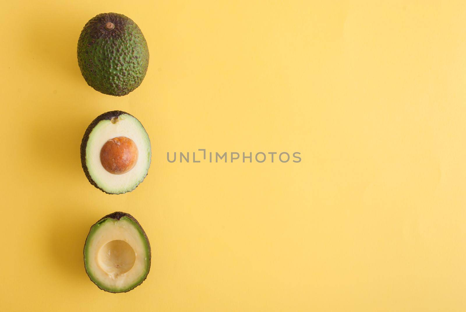 avocado whole and half on yellow background. High quality photo