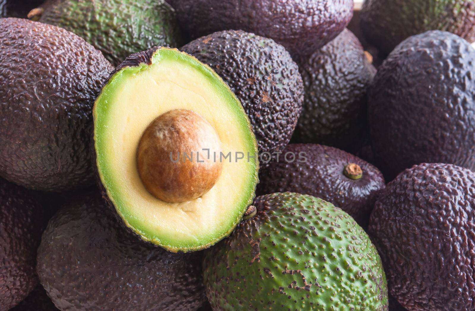 bunch of avocado haas with one half cutted on top. High quality photo