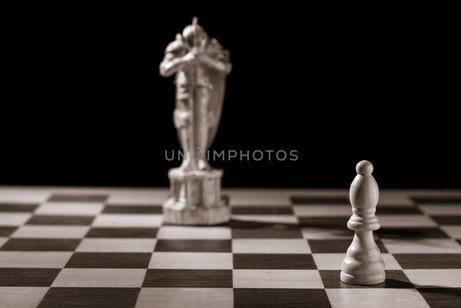 Classic white bishop and the same chess piece in the form of medieval figure on the background. Selective focus on classic piece