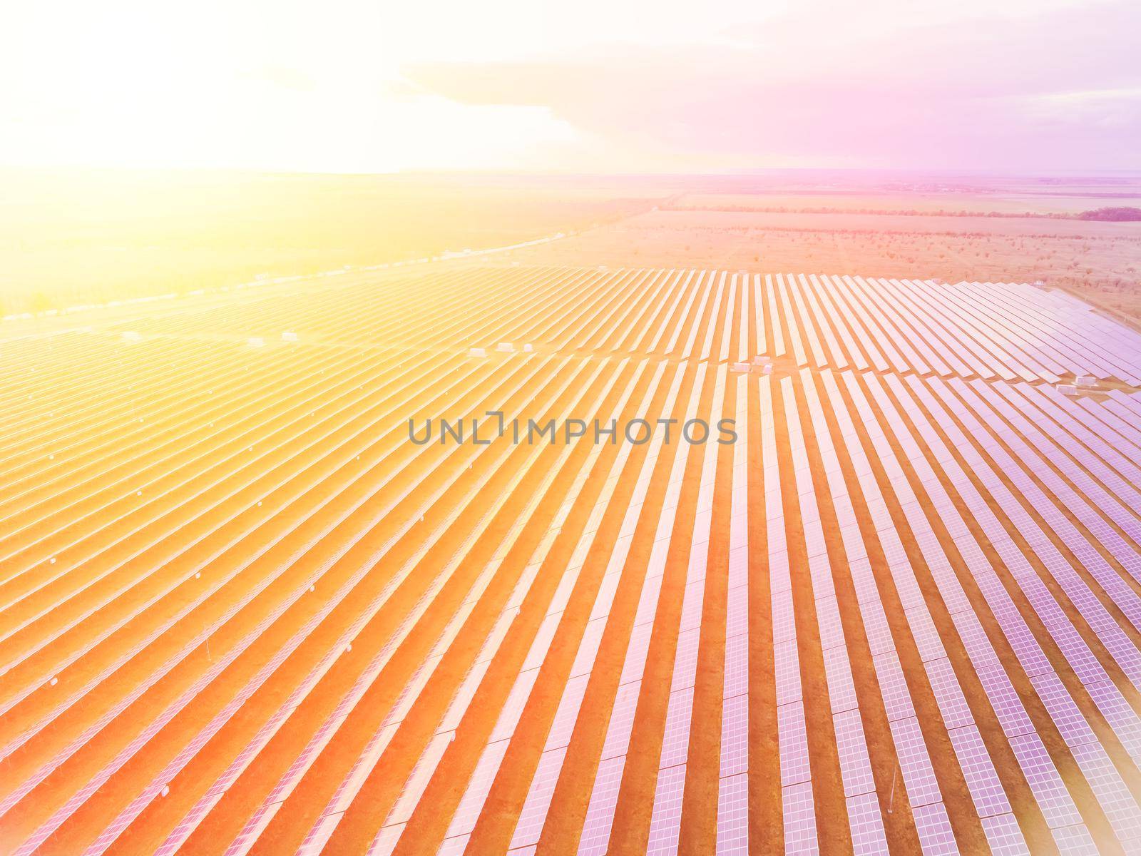 Aerial top view of a solar panels power plant. Photovoltaic solar panels at sunrise and sunset in countryside from above. Modern technology, climate care, earth saving, renewable energy concept