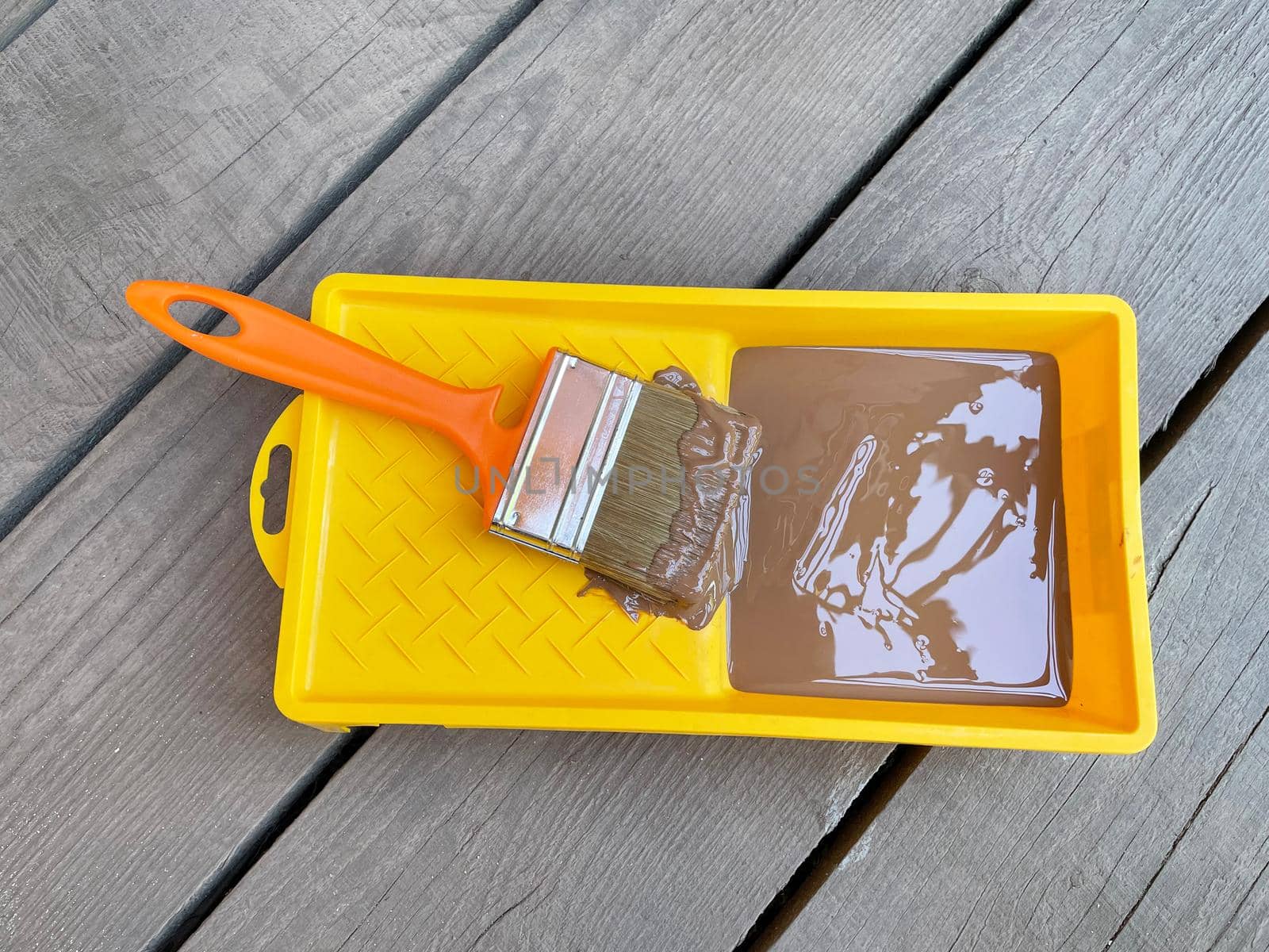 Yellow tray of green paint with brush on wooden background by BEMPhoto