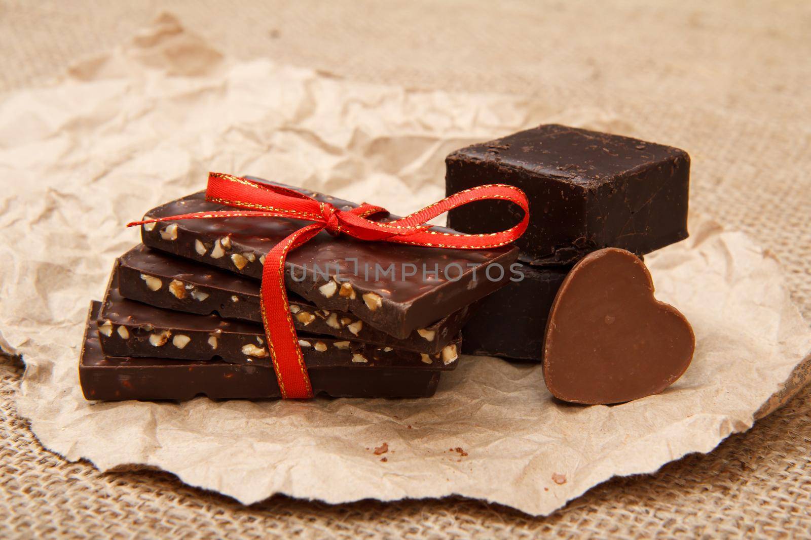 Chocolate bars with nuts and chocolate candies rectangular shape and in shape of heart on pack paper