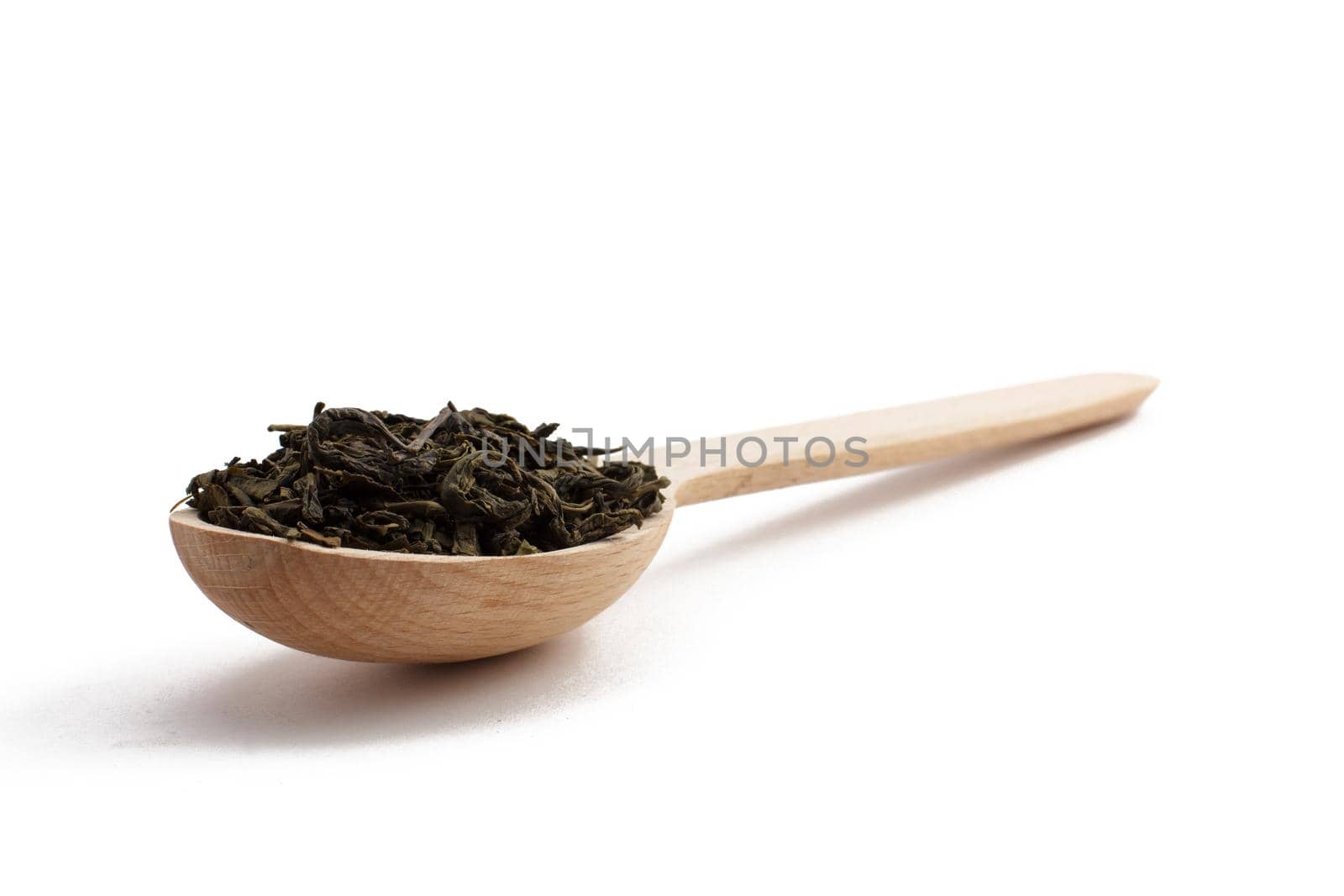 Wooden spoon with dry leaves of green tea on white isolated background