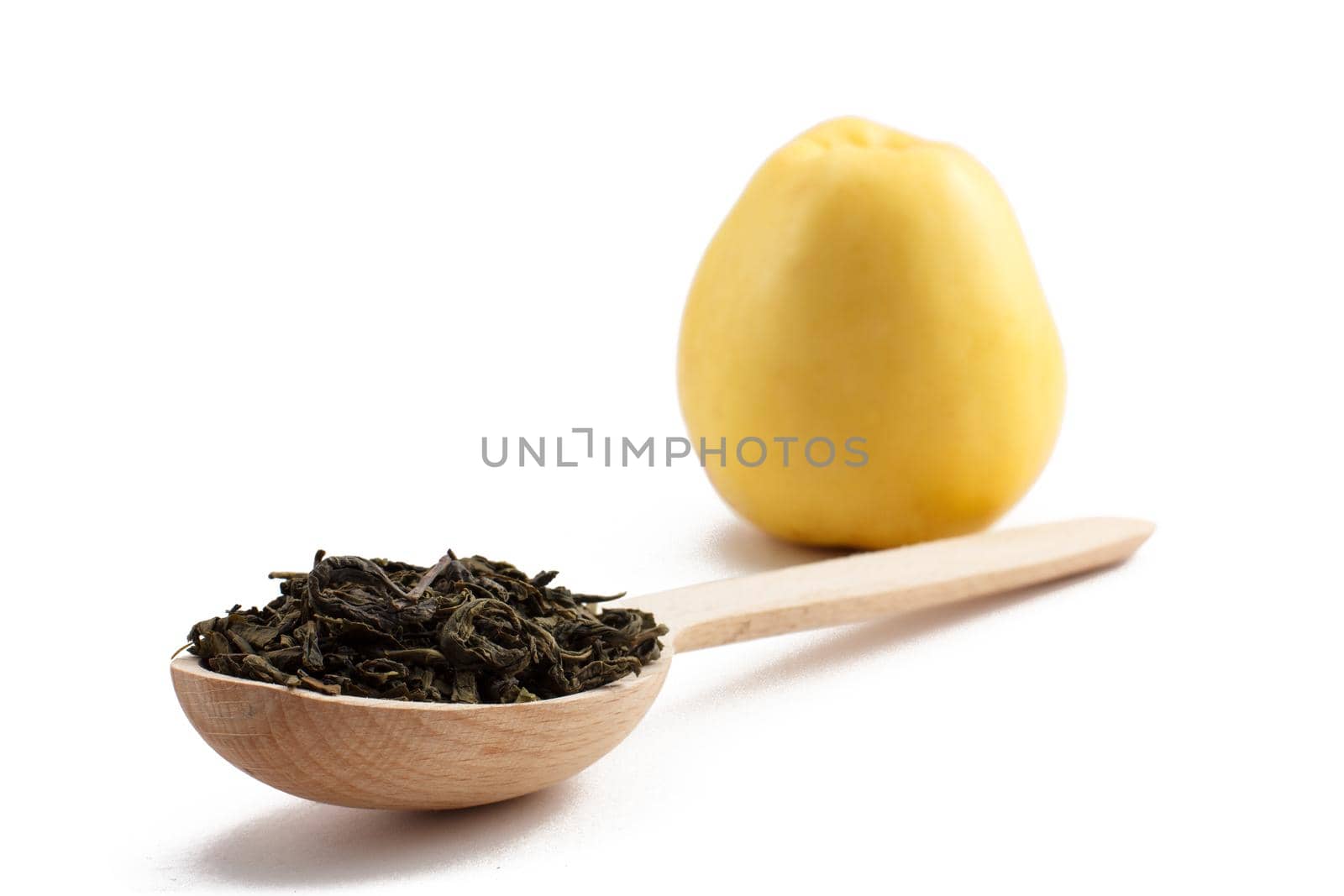 Wooden spoon with dry leaves of green tea and yellow apple on white isolated background