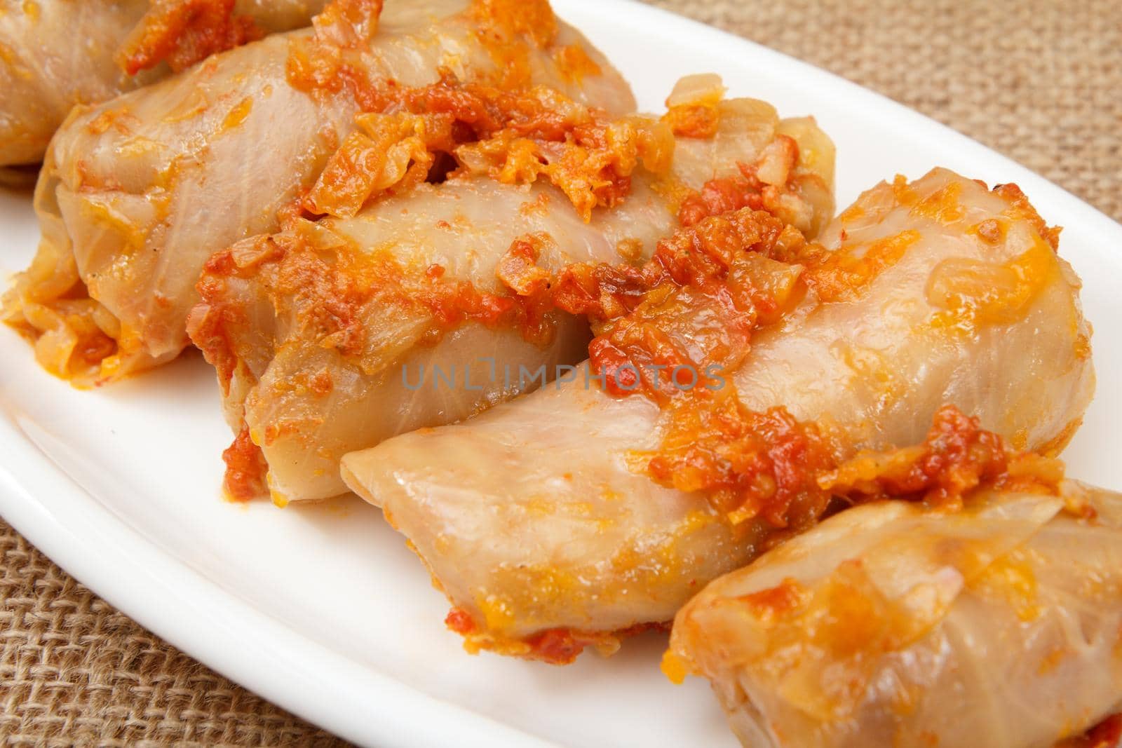 Delicious homemade cabbage rolls stuffed with rice and meat in white dish on sackcloth