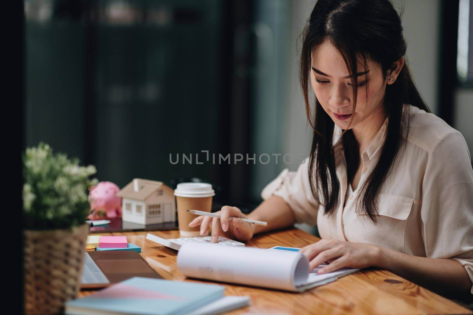 Portrait asian businesswoman or lawyer accountant working financial investment on office, using calculator analysis finance document report real estate and home loan insurance by nateemee