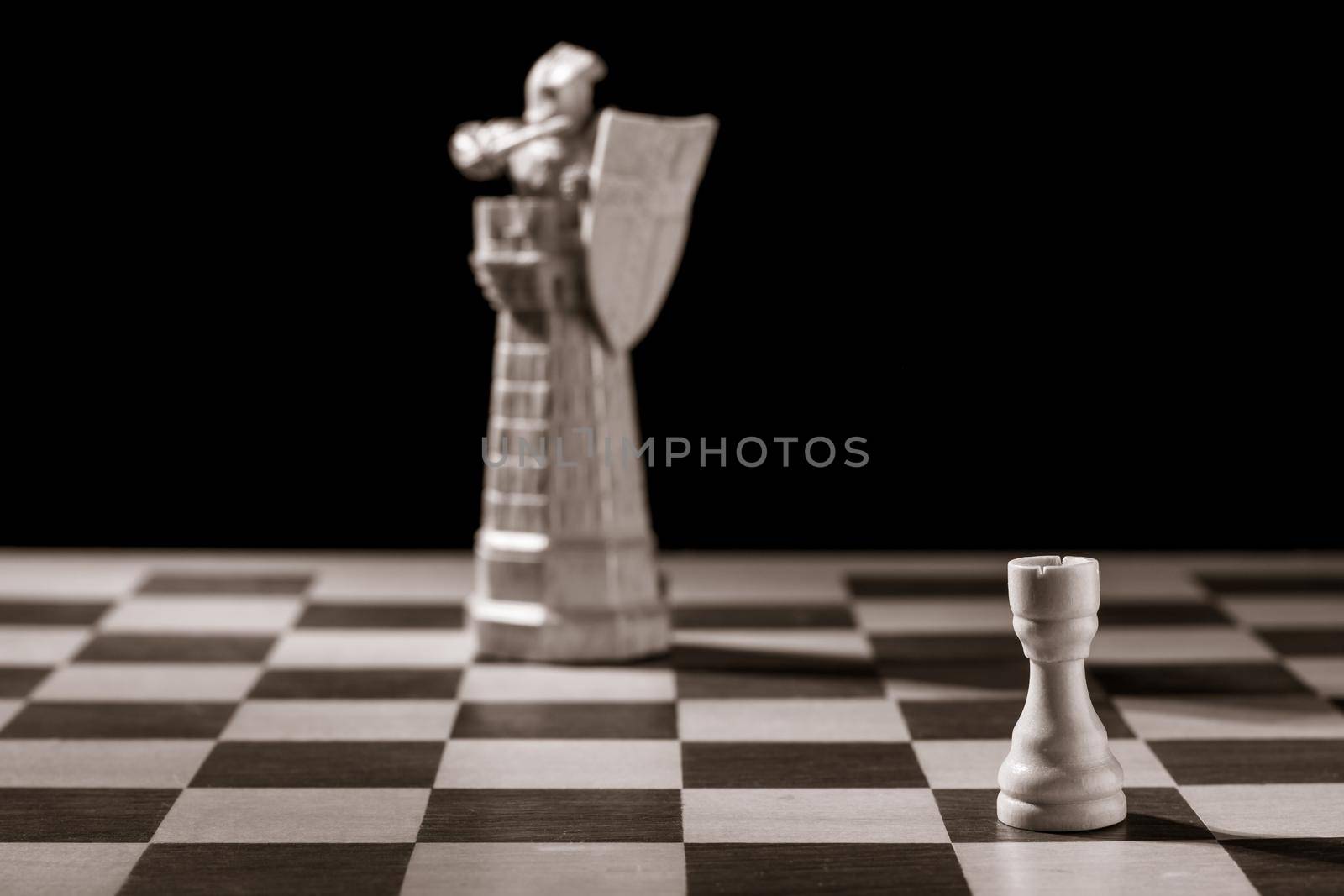 Classic white rook and the same chess piece in the form of medieval figure on the background. Selective focus on classic piece