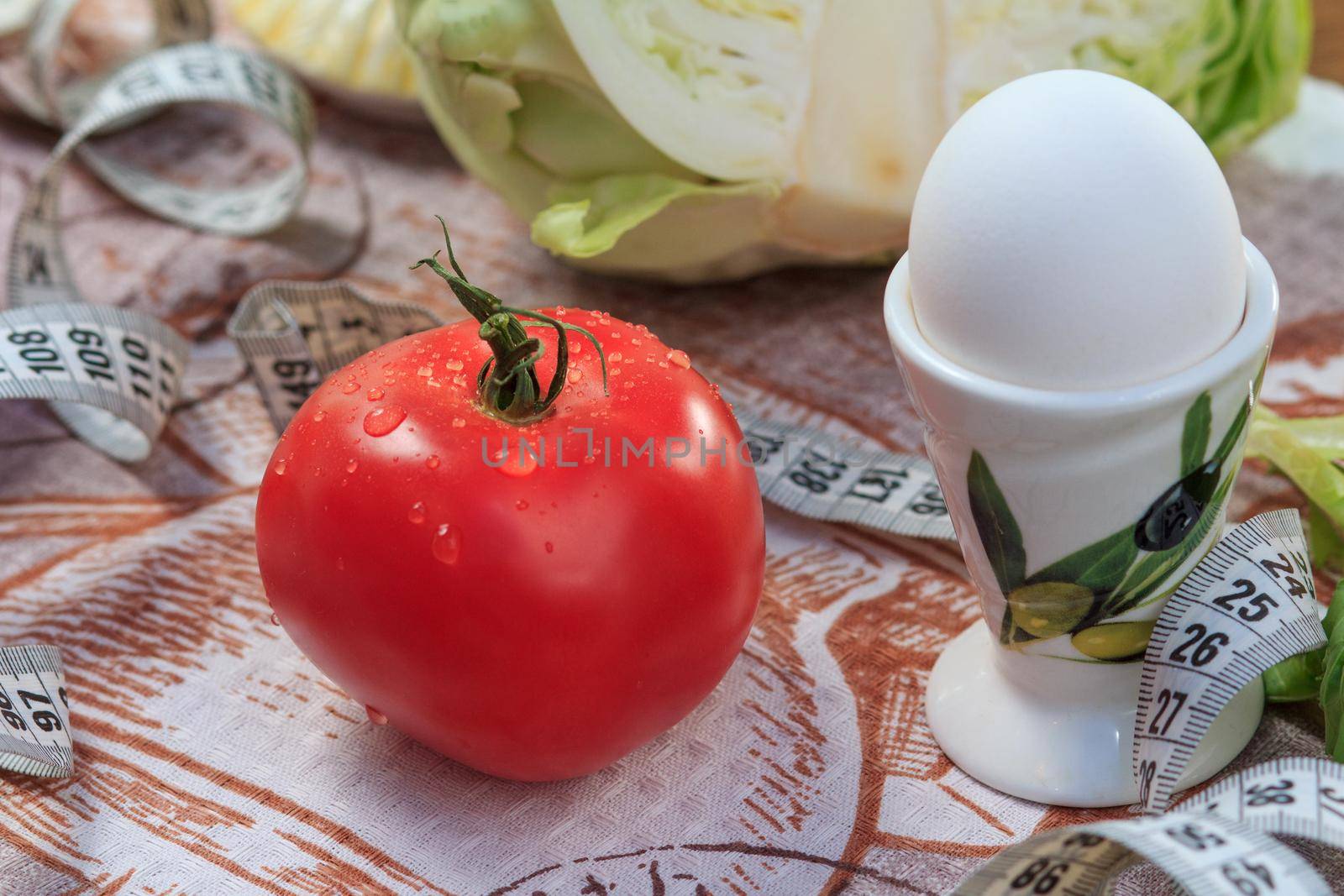 Nice red tomato, egg, cabbage and ruler on the table