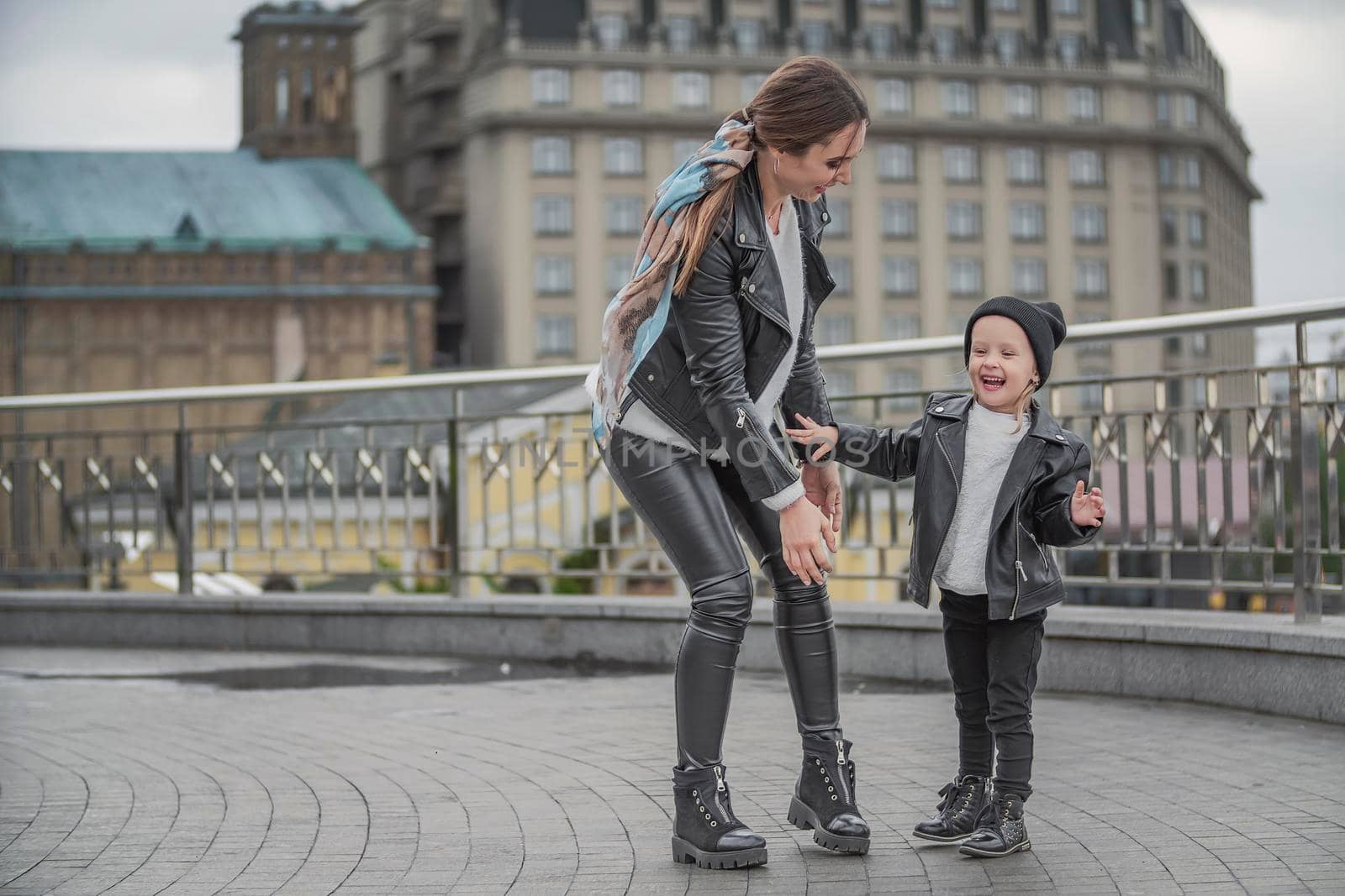 mother and daughter are walking around the city near the iron railings