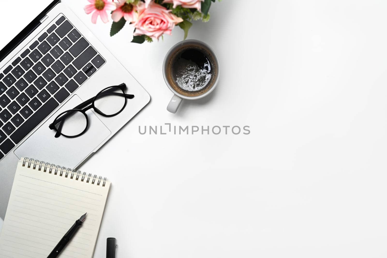 Laptop computer, eyeglasses, notebook and coffee cup on white background.