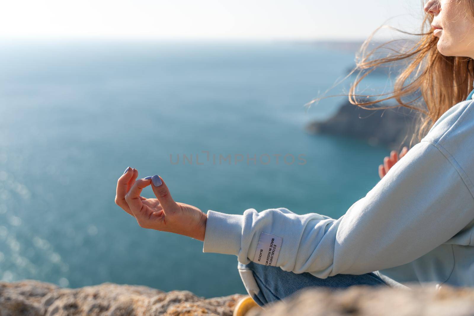 yoga, gesture and healthy lifestyle concept - hand of meditating yogi woman showing gyan mudra over sea sunset background.