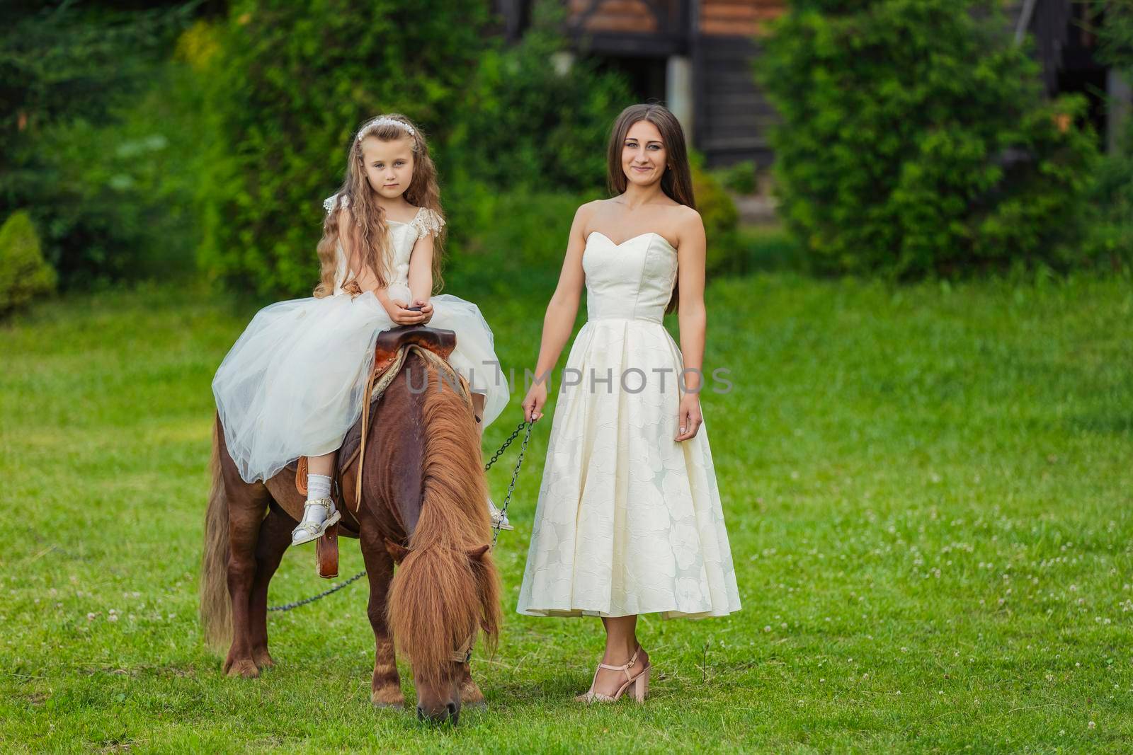 mother with daughter and pony walking in the yard