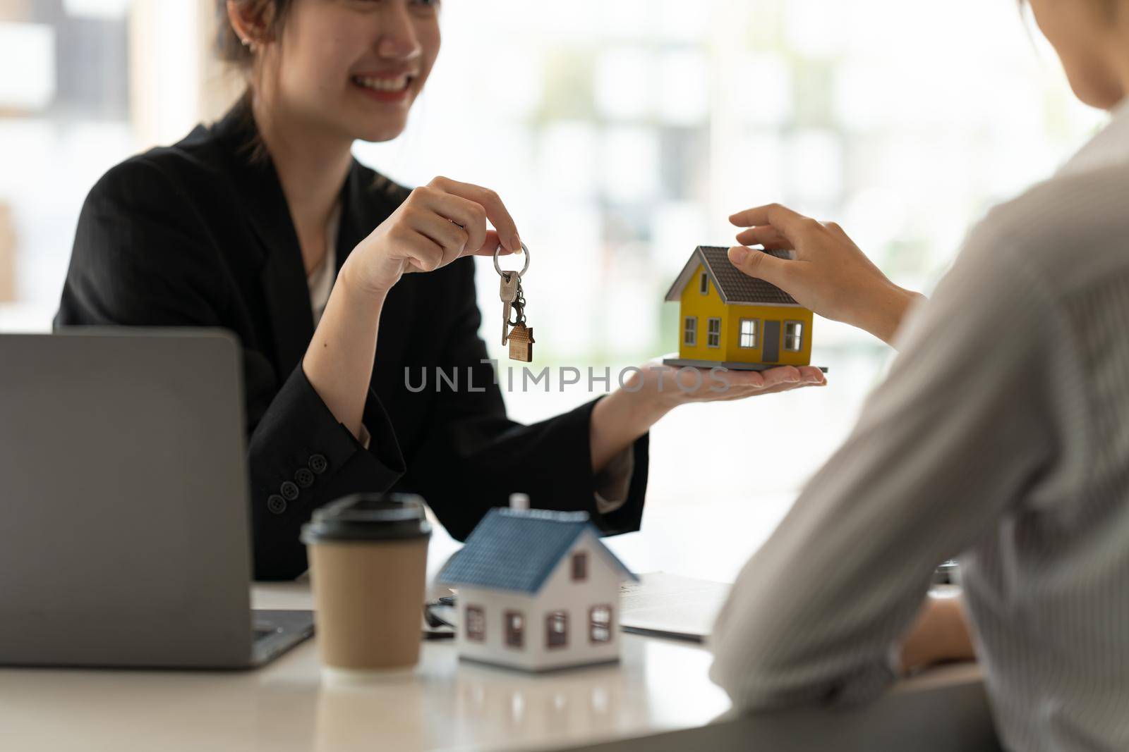 real estate agent holding house key to his client after signing contract agreement in office,concept for real estate, moving home or renting property by nateemee