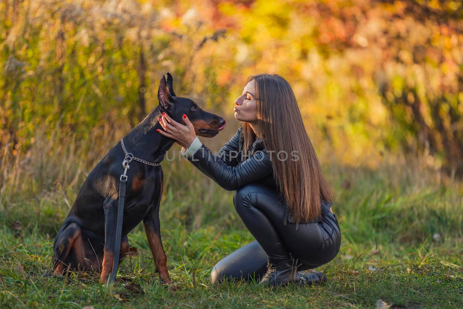 girl sitting near a doberman dog breed in nature