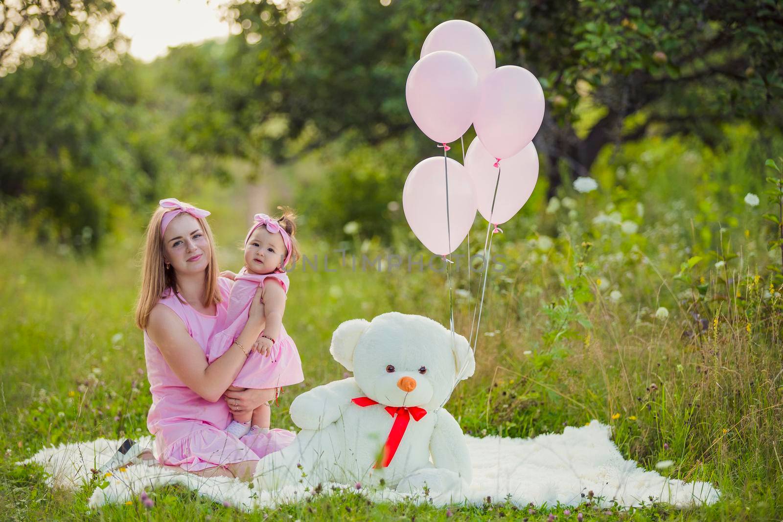 mother and daughter in pink dresses and with pink balloons in nature