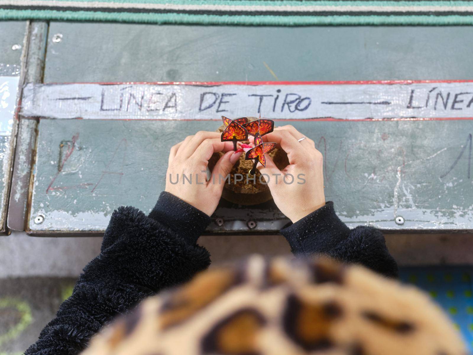 Hands of a girl sticking darts into a cork on the shooting line of a fair stall by WesternExoticStockers