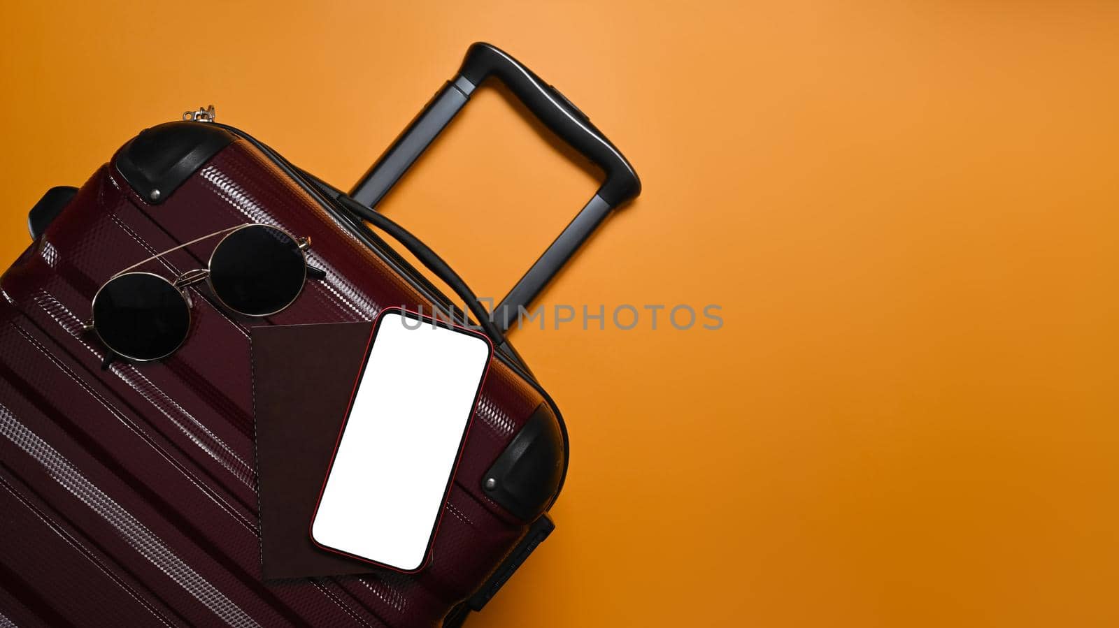 A suitcase with smart phone and sunglasses on yellow background with copy space. Preparing for the summer vacations.