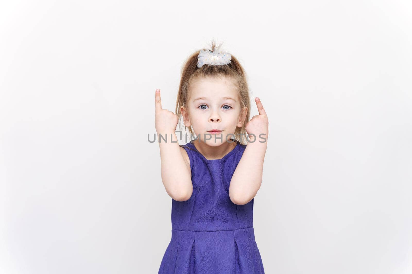 emotional little girl in a blue dress. thumbs up. light background