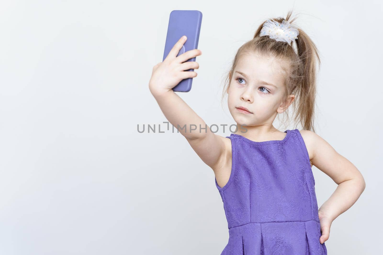 portrait of a cute 5 year old girl with a smartphone on a light background by Lena_Ogurtsova