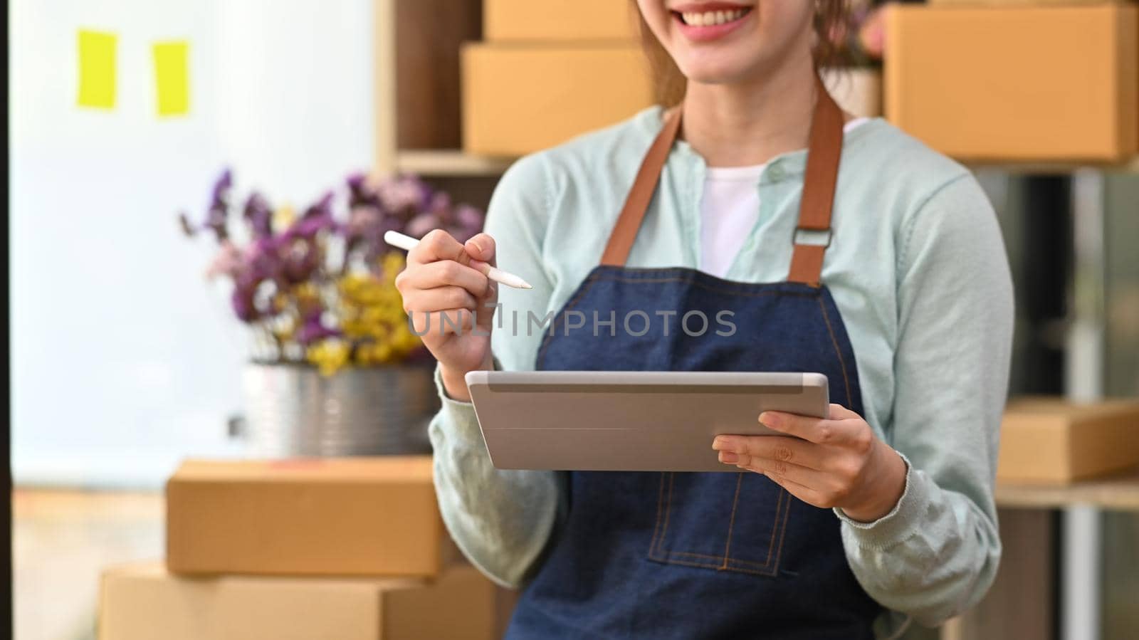 Young female startup business owner working with digital tablet for checking order on internet.
