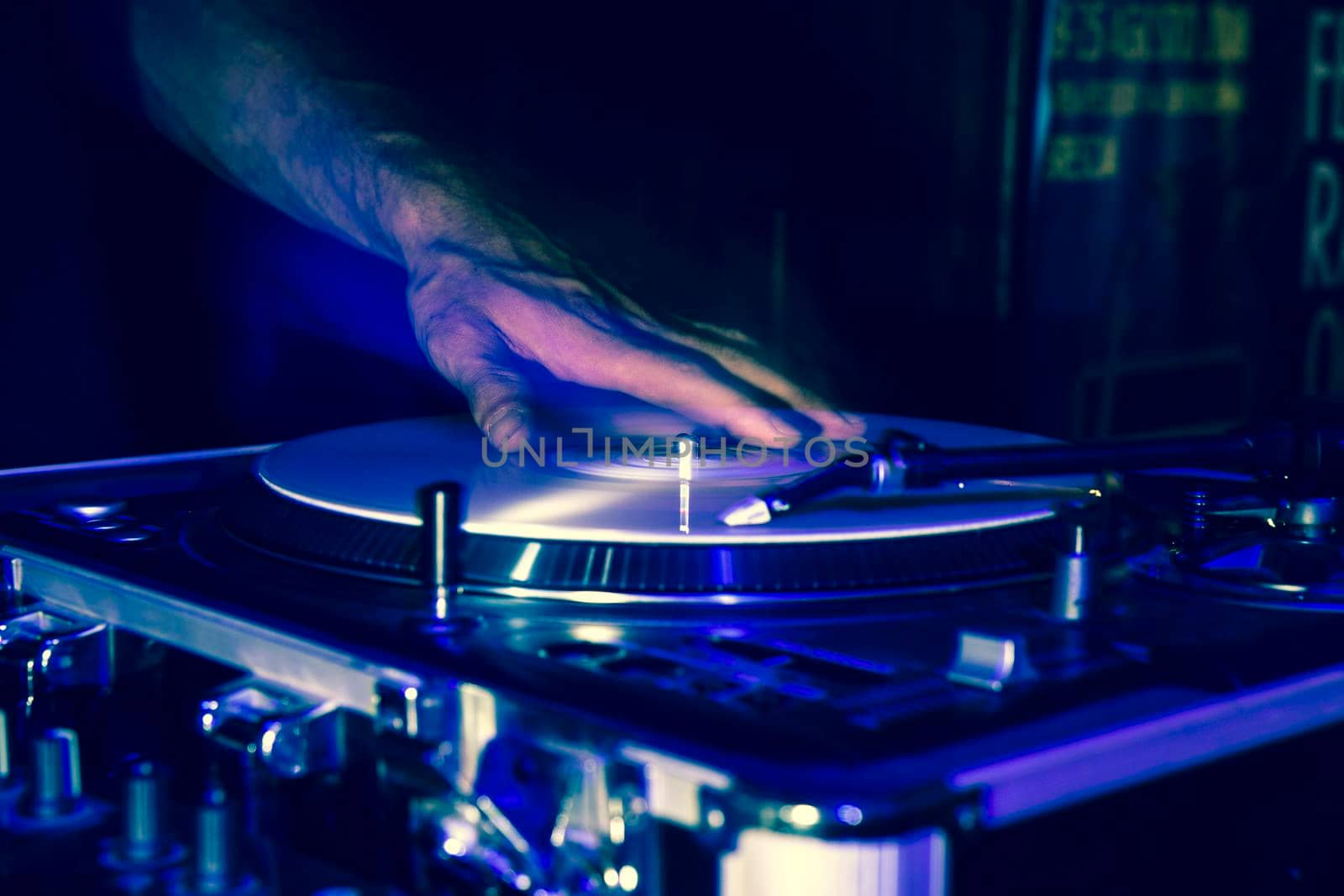 Hands of a DJ while playing vinyl records during a party, the hands are moving and are double for a strobe effect of the flash while shooting