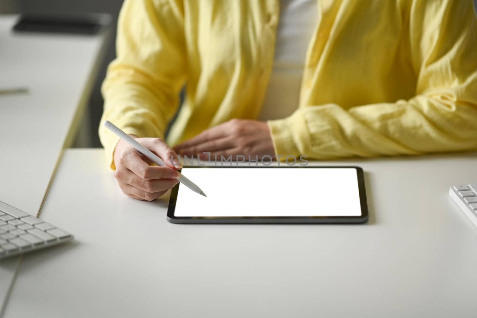 Young woman designer holding stylus pen and writing on digital tablet screen.