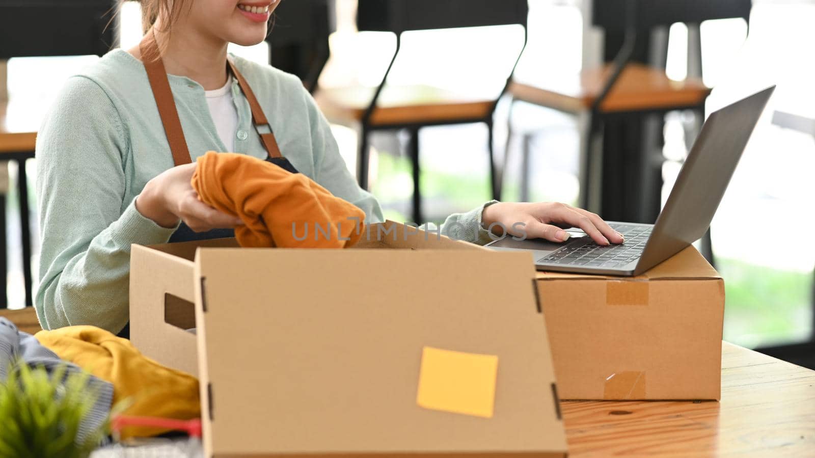 Start up online seller packing product in cardboard box for delivery to customers.