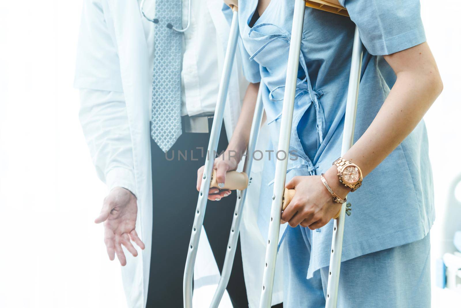 Doctor takes care of patient in crutch at hospital. Physical therapist and leg injury recovery concept.