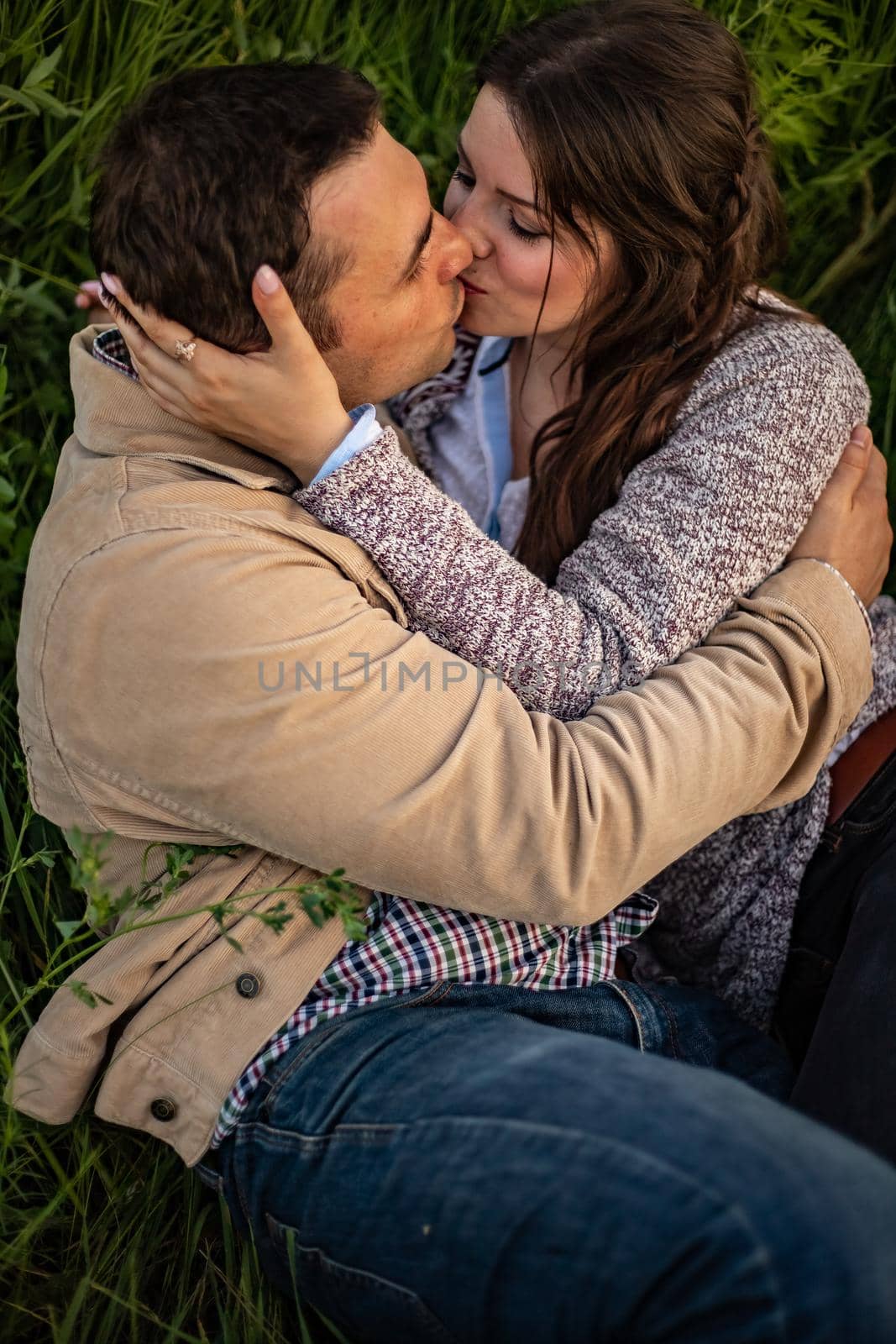 Stylish and modern couple lying on the grass and kissing.A couple in love lies on a green meadow and kisses