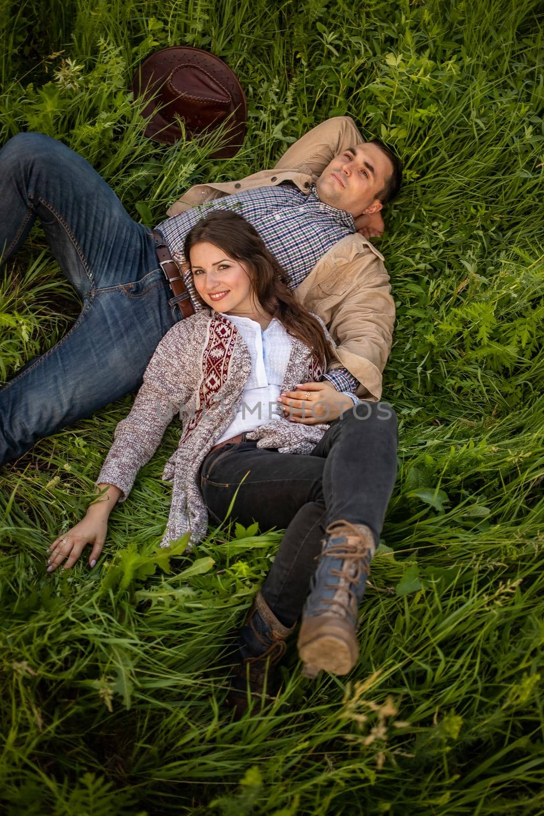 Young couple having picnic in meadow on bright sunny day. Man and woman enjoy each other's company by Anyatachka