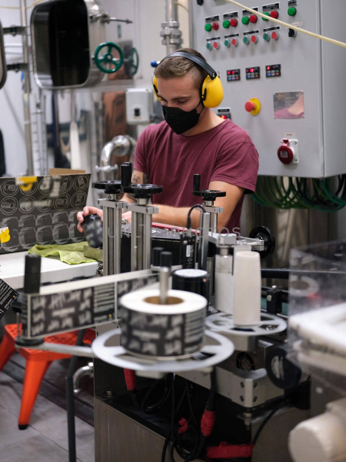 Vertical photo of a serious caucasian man working packing beer cans in a bottling factory