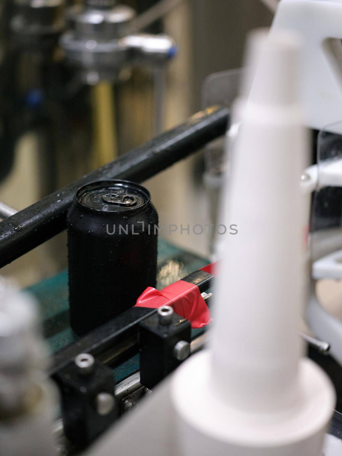 Vertical photo of a black can of craft beer in a row of a canning factory