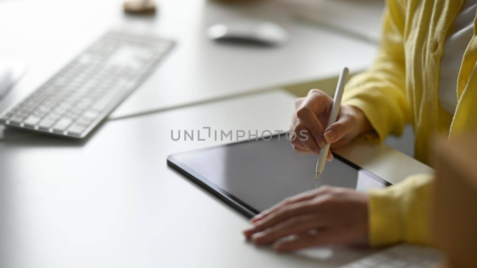 Female creative designer working with digital tablet on white table. Cropped shot.