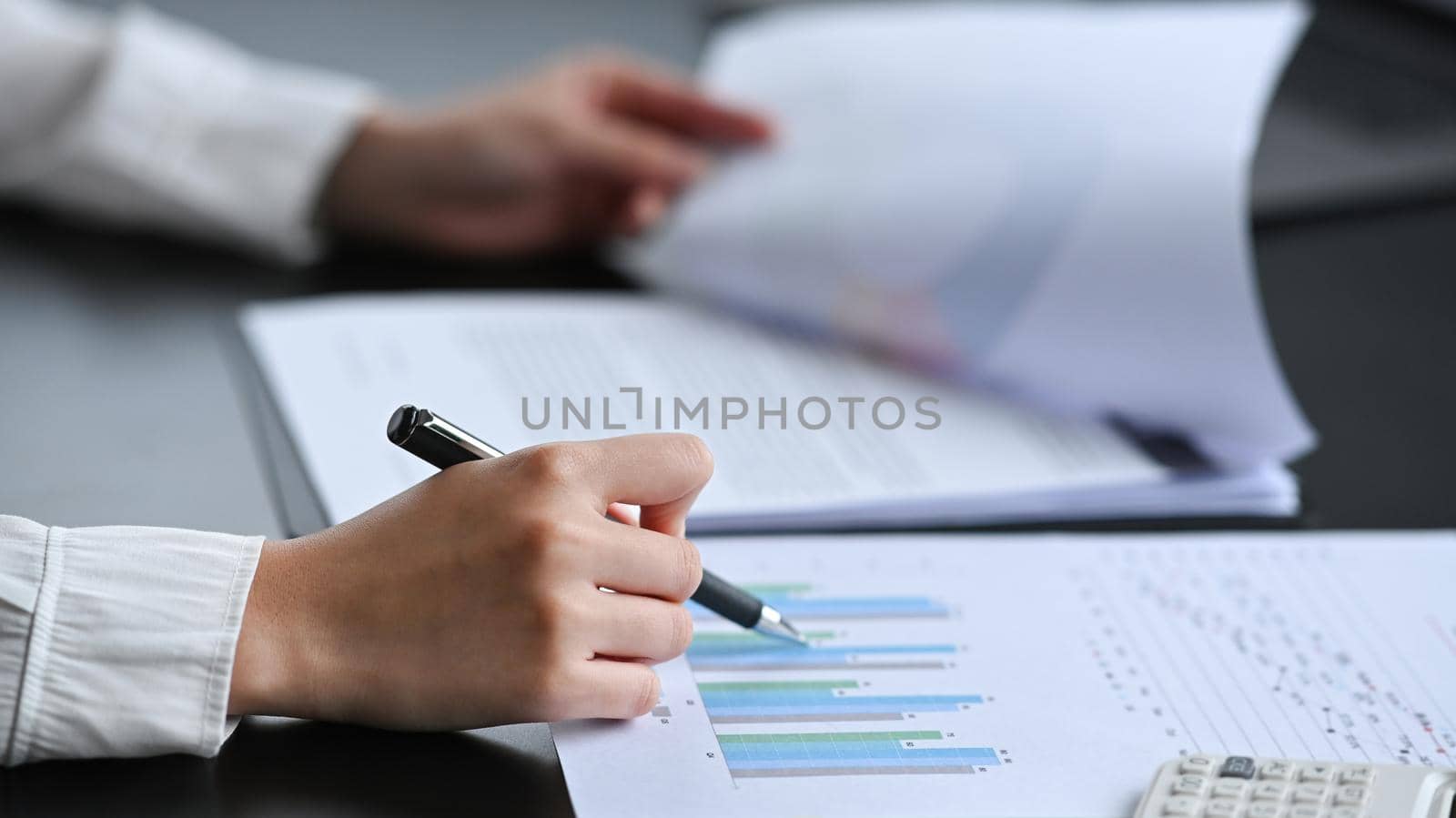 Close up view professional businesswoman holding pen and analyzing financial document.