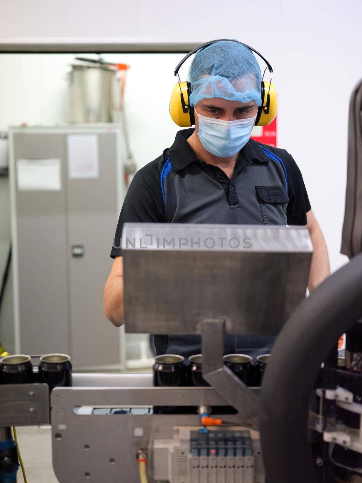 Vertical photo of a man working on a machine in the beer canning production line by WesternExoticStockers