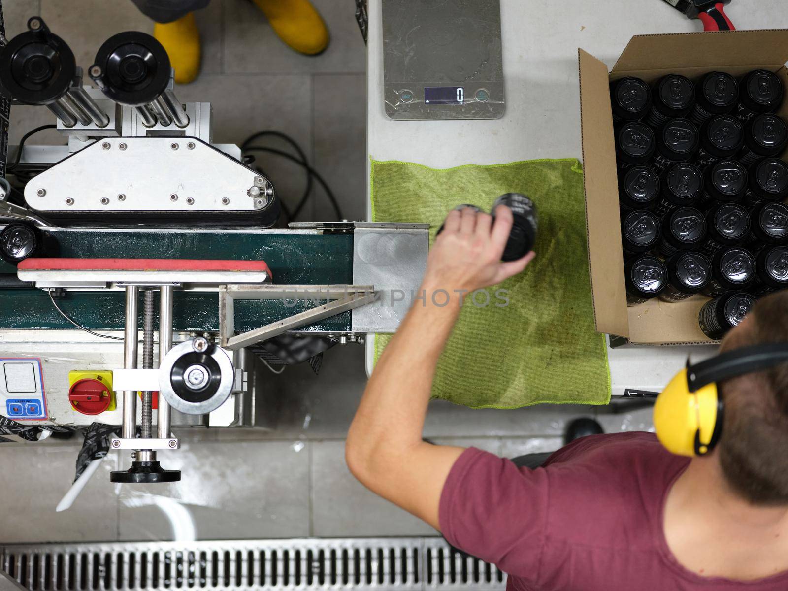 Top view of a male worker packing cans of beer packed in a cardboard box in a factory