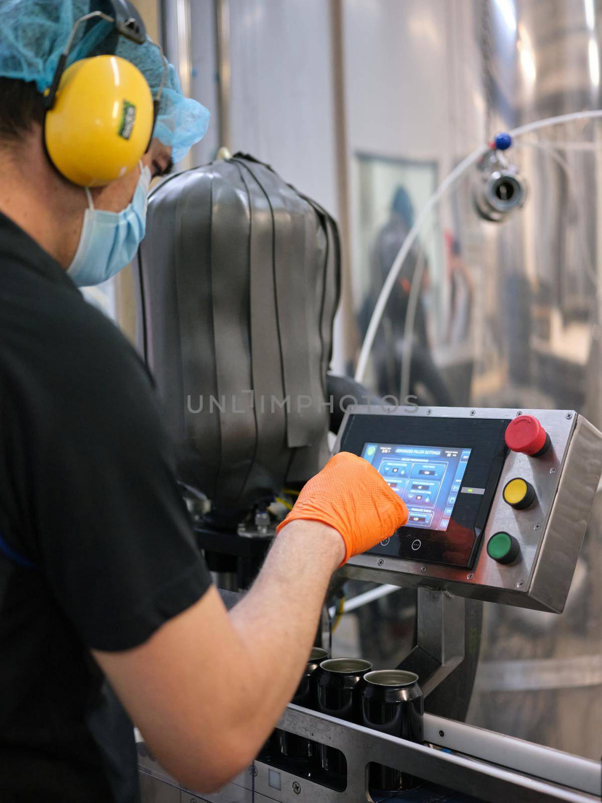 Worker with mask working with an electronic machine in a craft beer factory by WesternExoticStockers